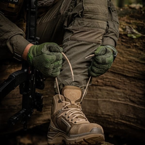 Sznurowanie butów wojskowych. na zdjęciu żołnierz zaciągający sznurówki na jasnych butach wojskowych.